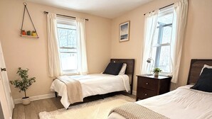 A bedroom with two beds, a wooden floor, a white rug, and a small plant. - Breezy Pad, Close to the Lake, with Hot Tub (St Joseph)
