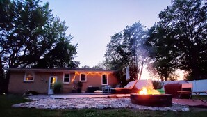 A house with a fire pit in the yard, surrounded by rocks and trees. - Breezy Pad, Close to the Lake, with Hot Tub (St Joseph)