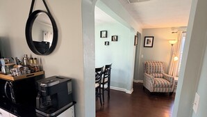A kitchen with a coffee maker, a microwave, and a countertop with jars. There is a dining area with chairs and a patterned armchair. - Breezy Pad, Close to the Lake, with Hot Tub (St Joseph)