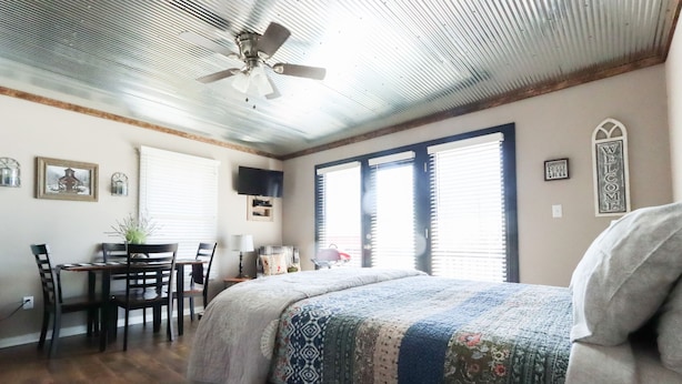 Une chambre à coucher avec un lit, un bureau, une chaise et un ventilateur de plafond.