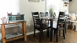 Un coin repas avec une table et des chaises en bois, un grille-pain vintage et une plante en pot.