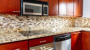 A kitchen with wooden cabinets, a microwave, a dishwasher, and a granite countertop. - Renovated Oceanview Condo w/ Spacious Layout, Covered Terrace & Swimming Pool Near Beach (Playa Flamingo)