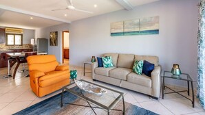 A modern living room with a sofa, coffee table, and a dining area with a table and chairs. - Renovated Oceanview Condo w/ Spacious Layout, Covered Terrace & Swimming Pool Near Beach (Playa Flamingo)