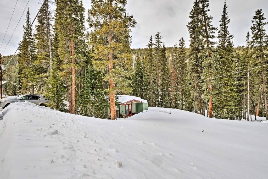 Paisaje nevado con una cabaña rodeada de altos pinos.