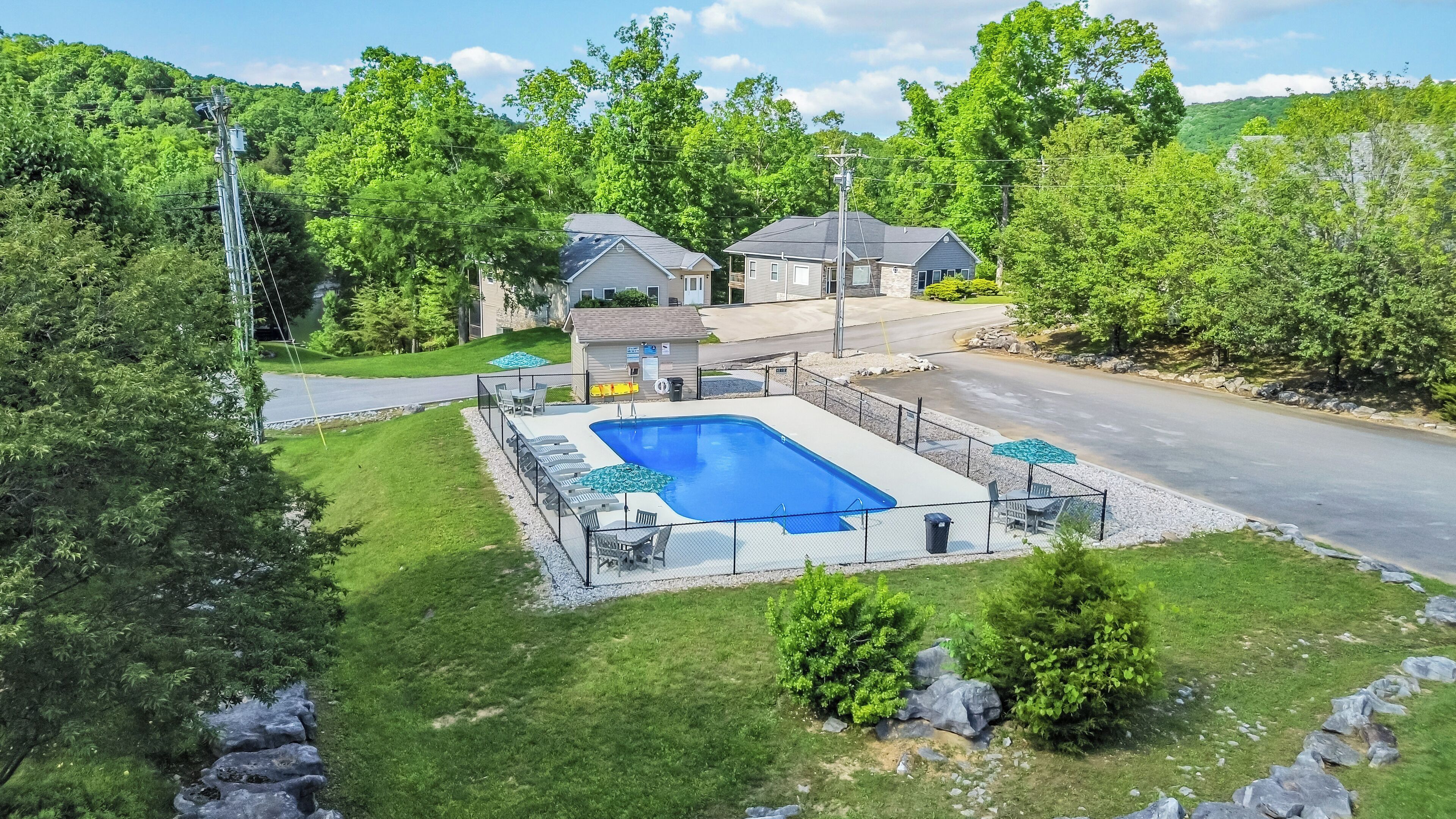 A residential property with a swimming pool, a covered patio, and a well-maintained lawn.