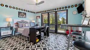 A bedroom with a bed, desk, chair, and a window with blinds.