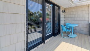A covered patio with a table and chairs, large sliding glass doors, and a light fixture.