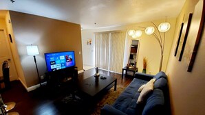 A living room with a flat-screen TV, a sofa, a coffee table, and a lamp. - ❤ Lovely condo! Walking distance to Strip with pool & spa (Las Vegas)