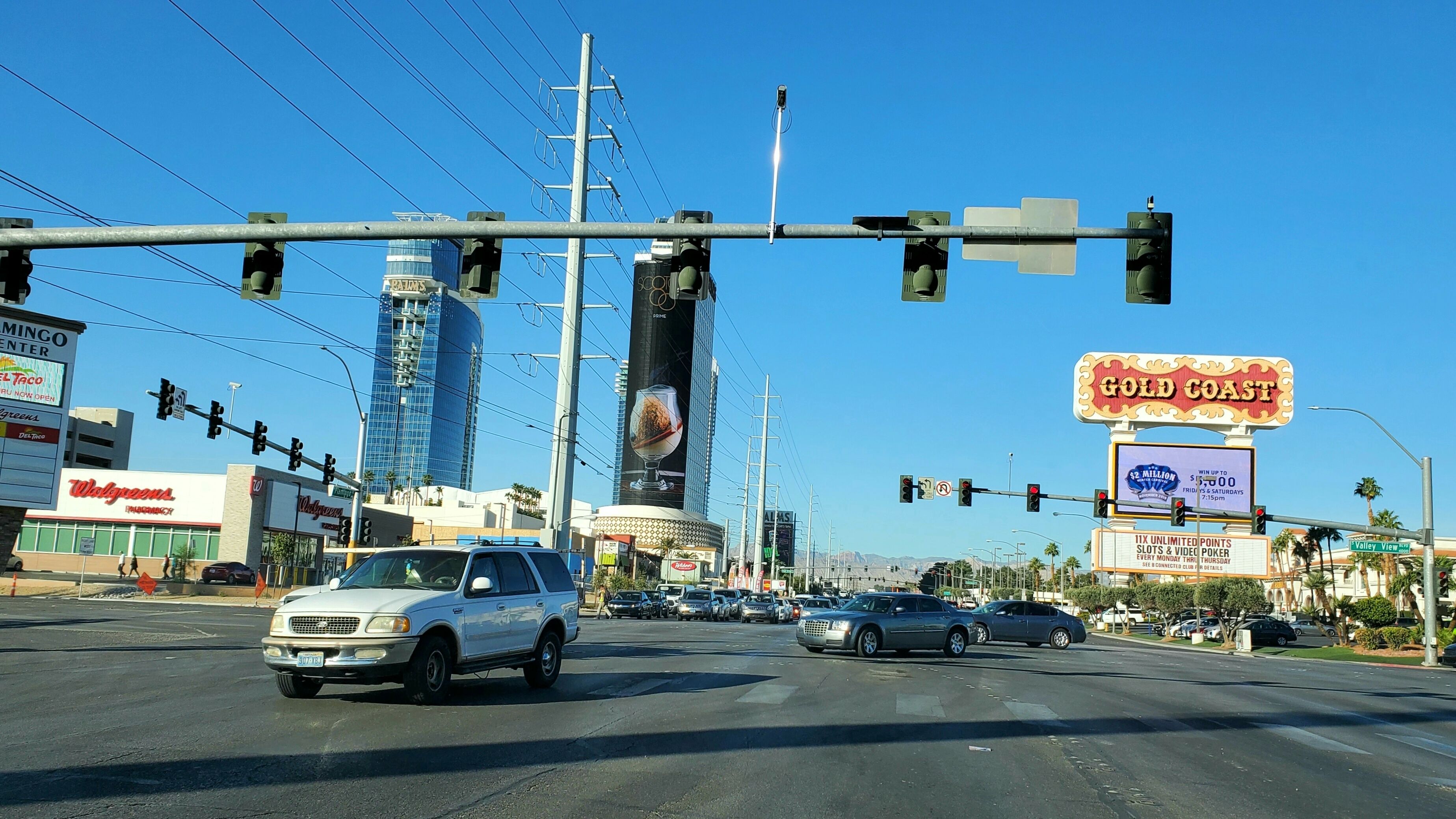 A busy intersection with traffic lights, a Walgreens store, and a Gold Coast casino sign.