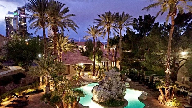 A resort pool area with palm trees, a rock formation, and a building in the background. - ❤ Lovely condo! Walking distance to Strip with pool & spa (Las Vegas)