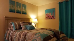 A hotel room with a bed, a nightstand, a lamp, and wall art depicting sailboats and the Eiffel Tower. - ❤ Lovely condo! Walking distance to Strip with pool & spa (Las Vegas)
