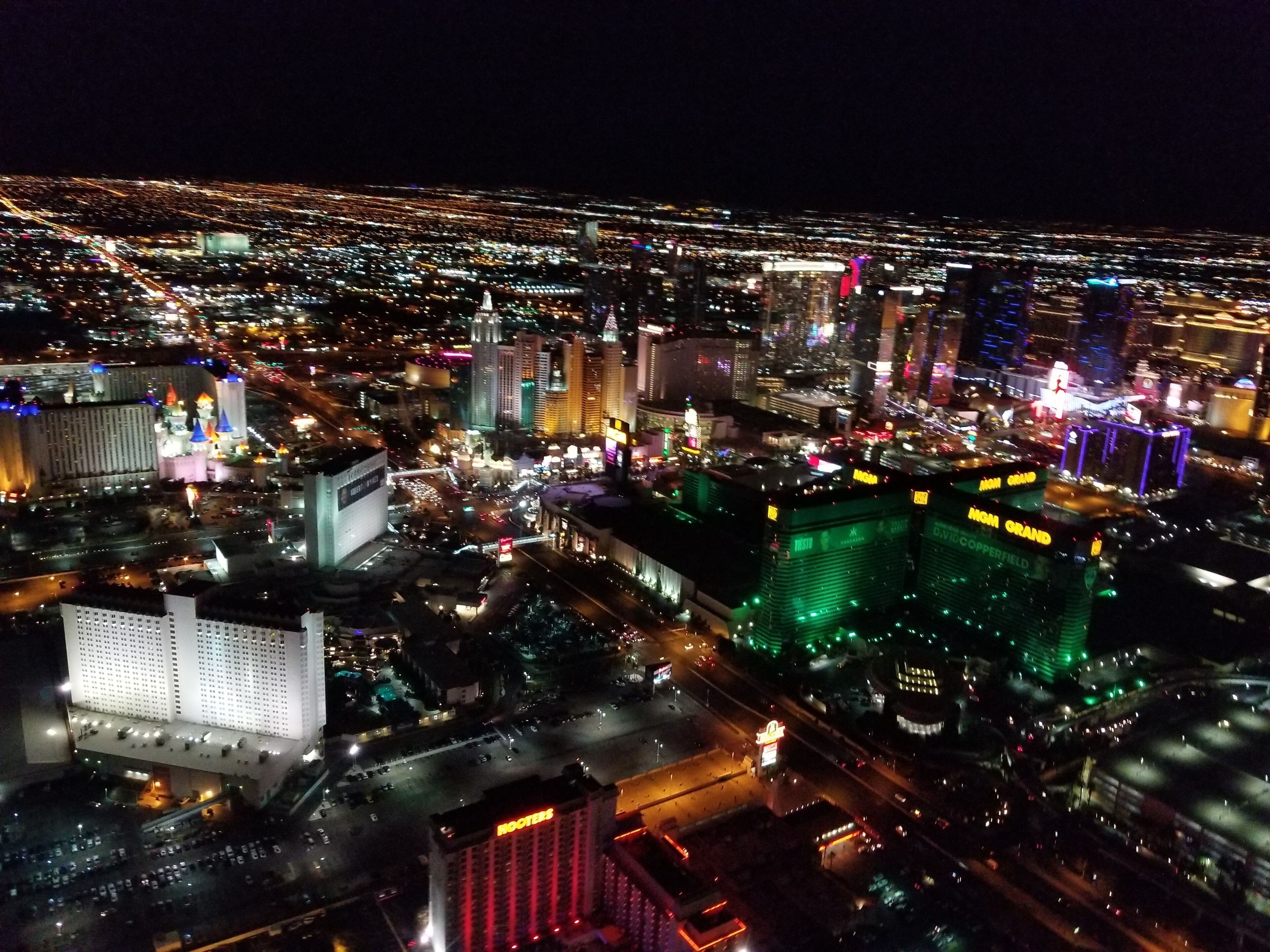 Une vue aérienne nocturne d’une ville, avec ses bâtiments imposants, dont un casino aux enseignes illuminées.