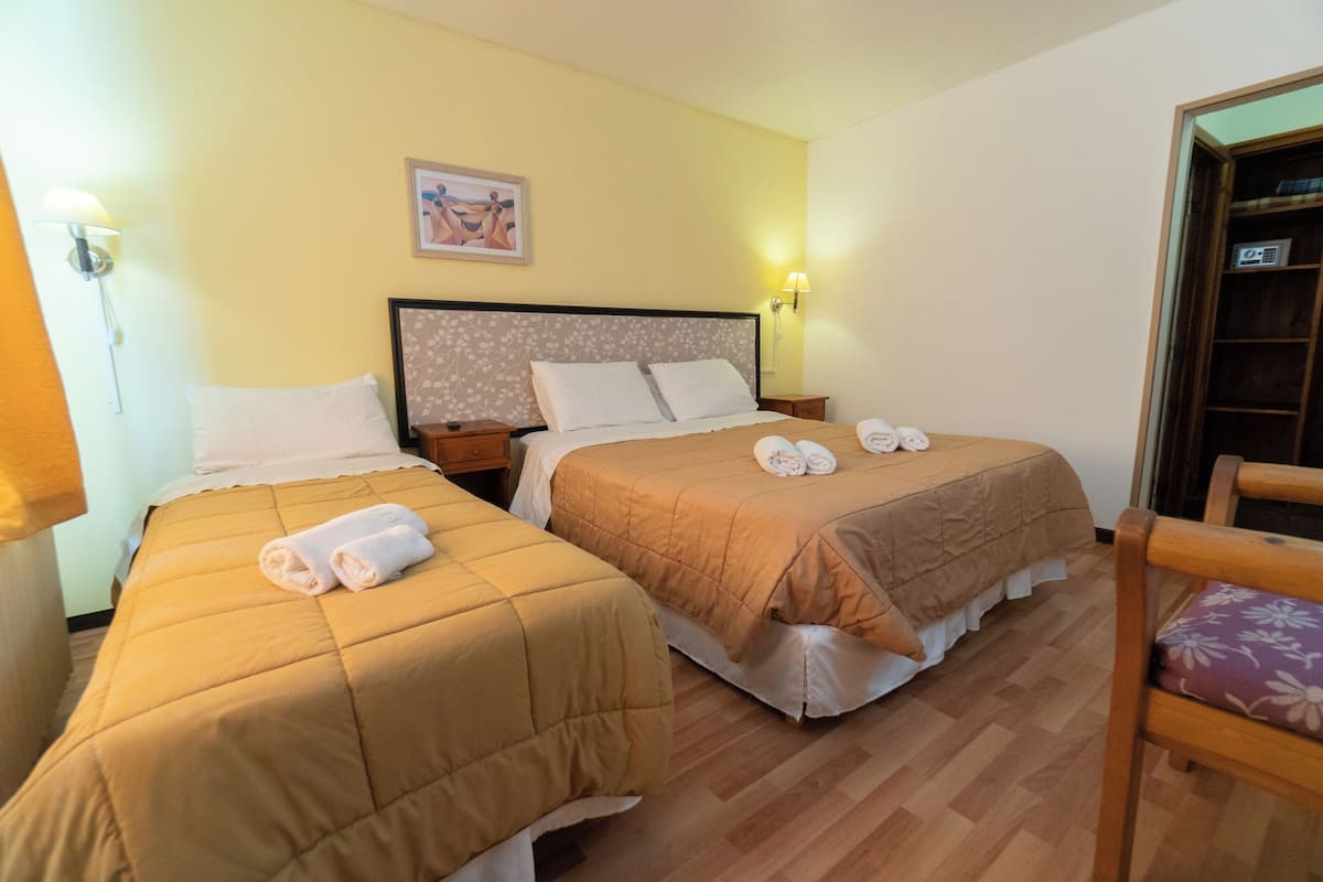Habitación de hotel con dos camas, suelo de madera y una silla.