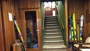A wooden interior with a staircase, skis, and a chair. - Hosteria La Pastorella (San Carlos de Bariloche)