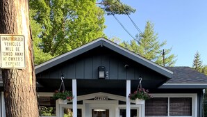 A small building with a porch, a sign indicating 15-minute parking for resort check-in, and a sign warning unauthorized vehicles will be towed.