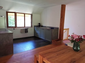 Eine moderne Küche mit grauen Schränken, einem Holztisch und einem Fenster mit Blick ins Grüne.