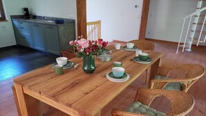 A wooden dining table with green and white plates, cups, and a vase with flowers. - Loft "le grenier" (Wolfgantzen)