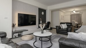 A modern living room with a flat-screen TV, a round coffee table, leather sofas, and a dining area with a table and chairs. - 2 min to MRT, 4B2b Shopping/Restaurant District (Taipei)