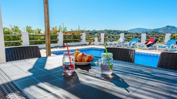 A poolside table with drinks and a plate of fruit, overlooking a pool and mountains. - Cantoblanco I Viñuela by Ruralidays (Málaga)