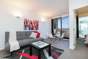 A modern living room with a grey sofa, a coffee table, and a colorful abstract painting.