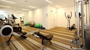 A gym with exercise equipment, a mirrored wall, and a striped floor.