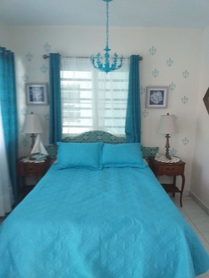 A bedroom with a large bed, two bedside tables, a chandelier, and curtains. - New beach front property  (Patillas)