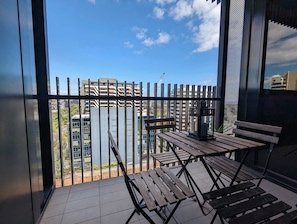 A balcony with a view of high-rise buildings, a wooden table, and a bench.