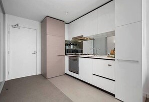 A modern kitchen with white cabinets, a microwave, stove, and a sink.