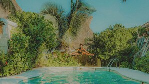 Une piscine entourée d’une végétation luxuriante et de palmiers.