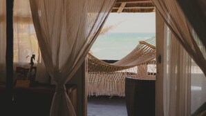 Une chambre avec un lit, une fenêtre ornée de rideaux légers et une vue sur la mer.
