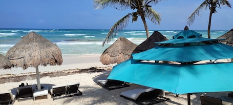 Playa privada, arena blanca, sillas reclinables de playa, sombrillas