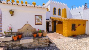 A traditional building with a white facade, a yellow section, and a cobblestone courtyard. - Sierra Tejeda  -  El Lagarillo Alcaucín by Ruralidays (Málaga)