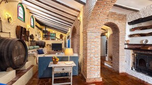 A rustic interior with exposed brick walls, a fireplace, wooden barrels, and a cozy seating area with a television and lamp. - Sierra Tejeda  -  El Lagarillo Alcaucín by Ruralidays (Málaga)