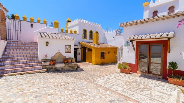 A courtyard with cobblestone flooring, a staircase with blue and white tiles, and buildings with white walls and yellow accents. - Sierra Tejeda  -  El Lagarillo Alcaucín by Ruralidays (Málaga)