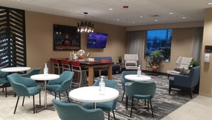 A hotel lobby with a dining area, seating arrangements, a television, and a large window. - Simple Suites Boise Airport (Boise)