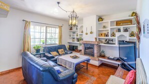 A living room with a sofa, a coffee table, a fireplace, and shelves with decorative items. - Laurel de Mijas by Ruralidays (Málaga)