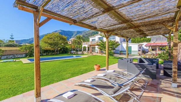 A poolside area with lounge chairs, a pergola, and a view of a mountain. - Laurel de Mijas by Ruralidays (Málaga)