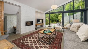 Ein modernes Wohnzimmer mit Kamin, großem Fenster und einer gemütlichen Sitzecke.
