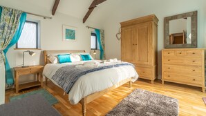 Un dormitorio con cama y armario de madera, un espejo y una ventana con cortinas.