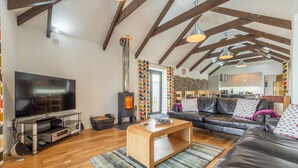 A spacious living room with a large TV, wooden coffee table, and a fireplace.