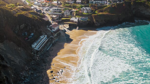 A coastal town with houses along the cliffside, a beach, and a boat dock.
