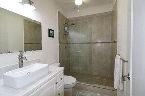 Une salle de bain moderne avec une douche à parois de verre, un lavabo blanc et des toilettes.