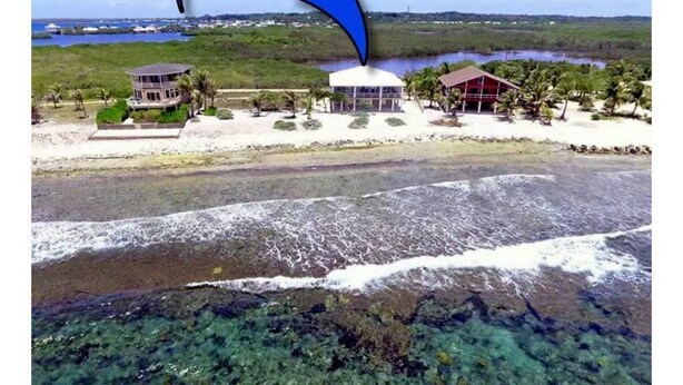 Un hôtel situé sur la côte, avec vue sur la plage, une piscine et un grand bâtiment doté d’un toit rouge.