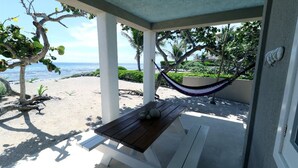 Un espace extérieur abrité, doté d’une table et de bancs en bois, d’un hamac et offrant une vue sur la plage et l’océan.
