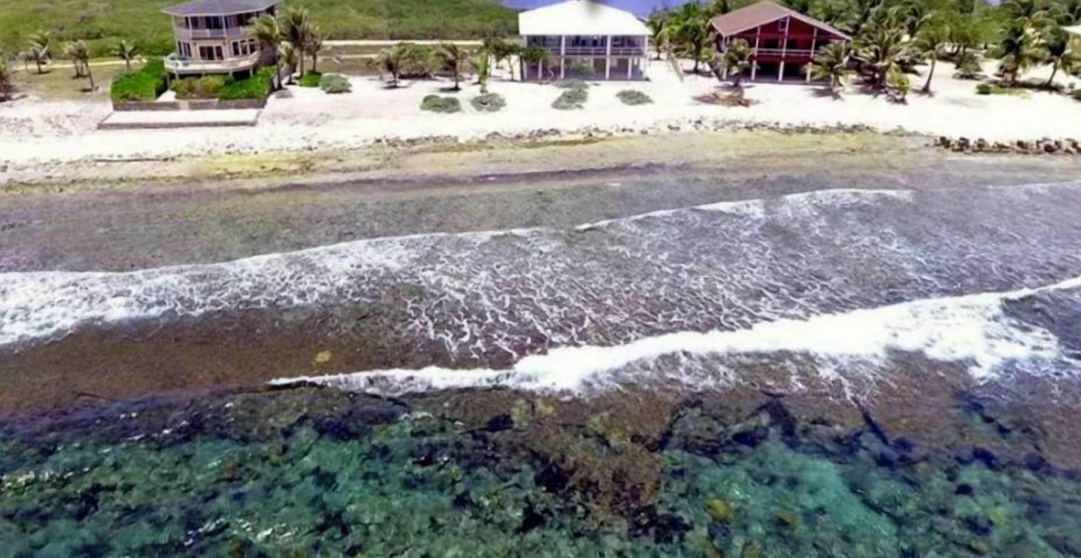 Un hôtel situé sur la côte, avec vue sur la plage, une piscine et un grand bâtiment doté d’un toit rouge.