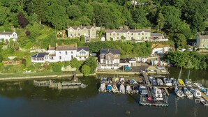 A riverside residential area with houses and a dock with boats. - This holiday home is situated right on the water’s edge within the Malpas Marina (Malpas)