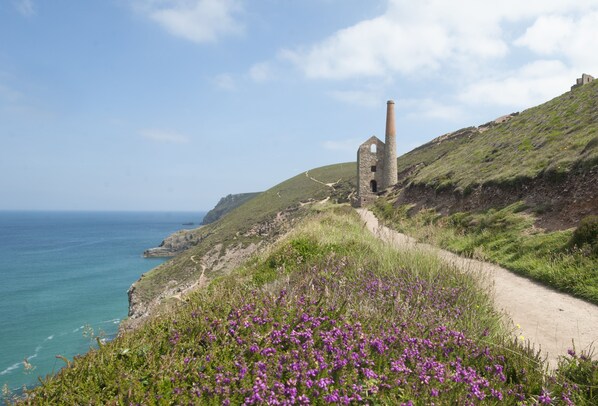 Ein Küstenpfad mit einer historischen Steinarchitektur und freiem Blick auf das Meer.