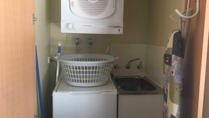 A compact laundry area with a washing machine, a drying machine, and a small sink.