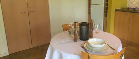 A dining area with a table set for two, a microwave above the cabinets, and a cabinet with a microwave on top.