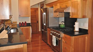 Una cocina con armarios de madera, un refrigerador de acero inoxidable, una estufa y un fregadero.